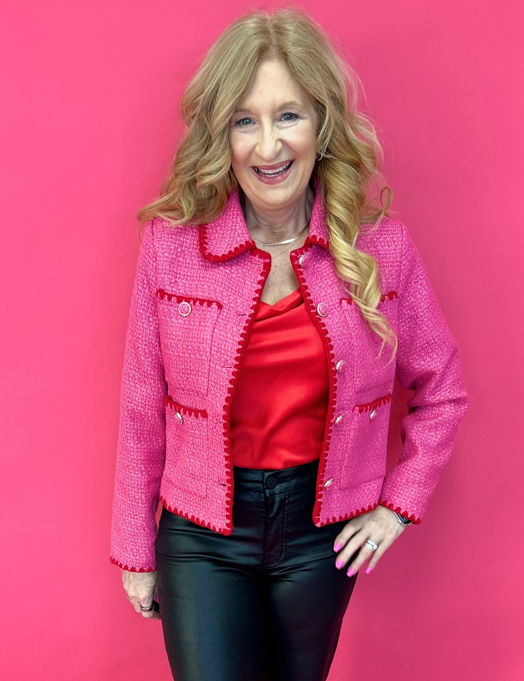 Woman wearing a fuchsia pink tweed jacket with contrast embroidered trim and a spread collar