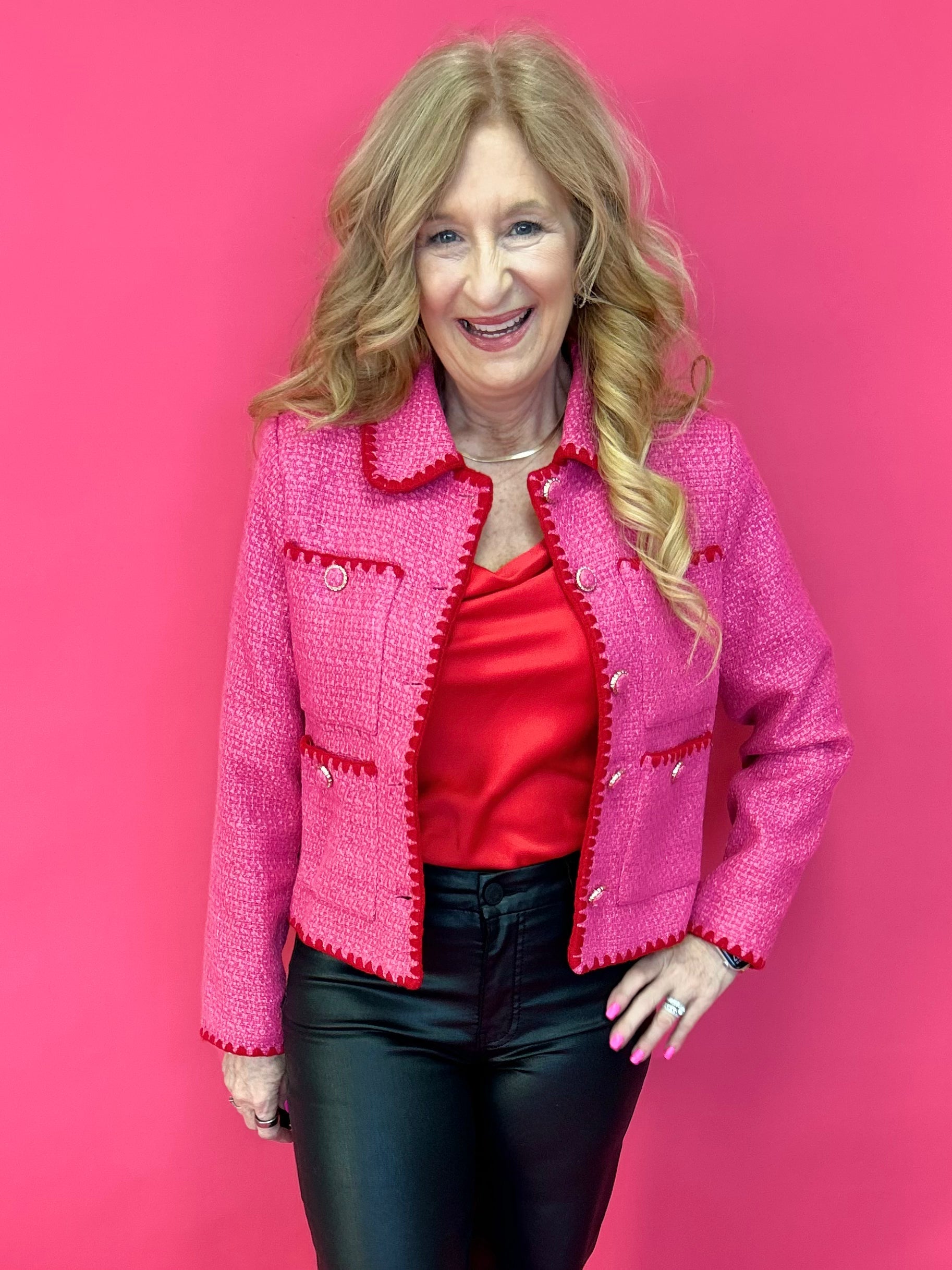 Woman wearing a fuchsia pink tweed jacket with contrast embroidered trim and a spread collar