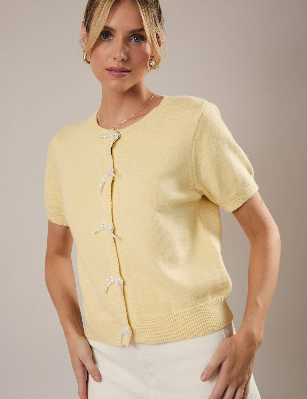 Woman wearing a light yellow cardigan against a neutral background