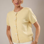 Woman wearing a light yellow cardigan against a neutral background