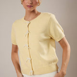 Woman wearing a light yellow cardigan against a neutral background