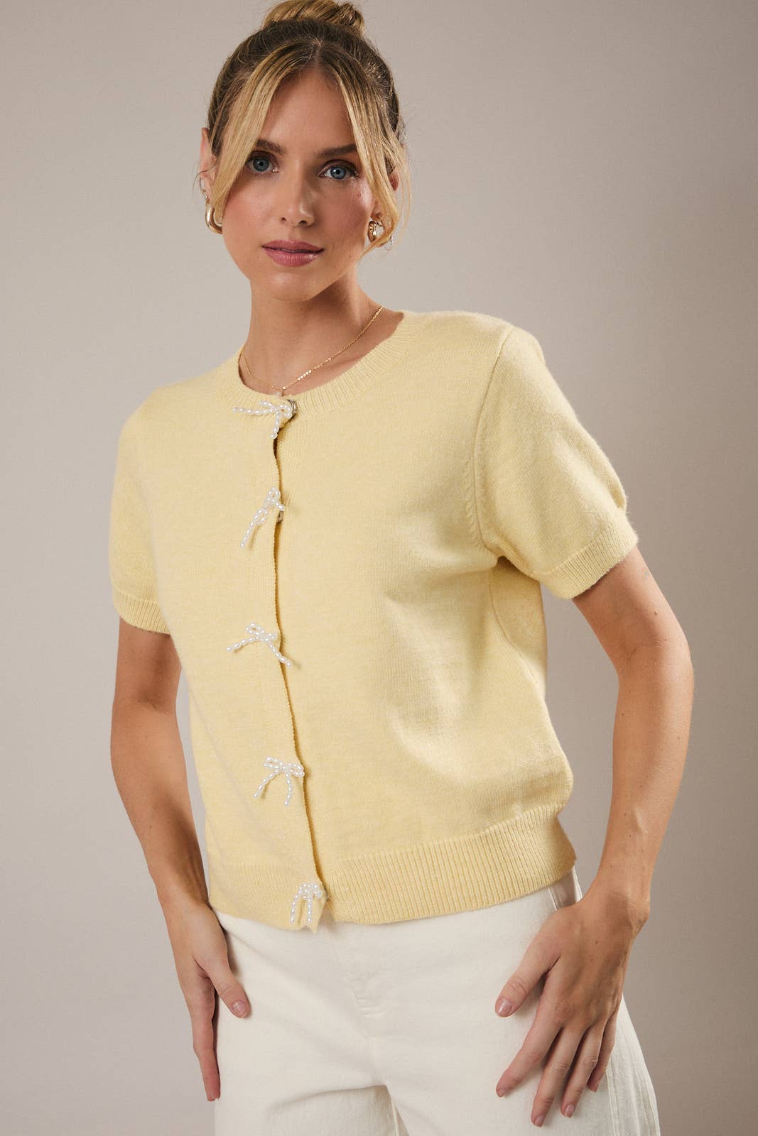 Woman wearing a light yellow cardigan against a neutral background