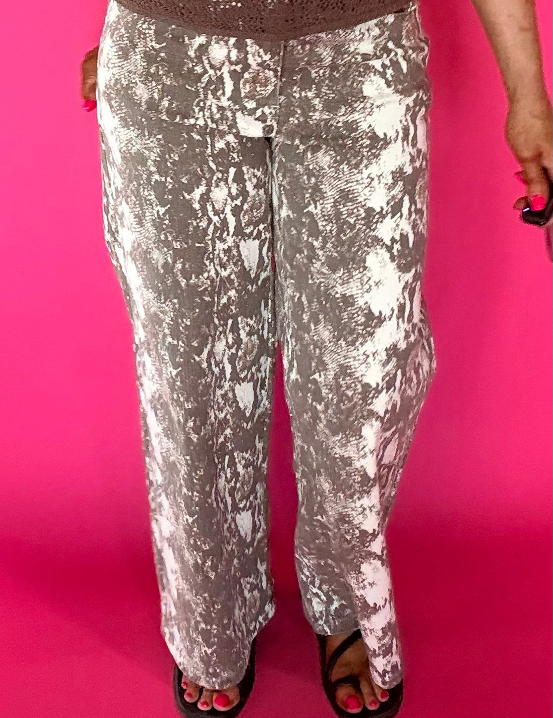 Woman wearing flowy ecru snake print wide leg pants with a fitted cream tee and heels