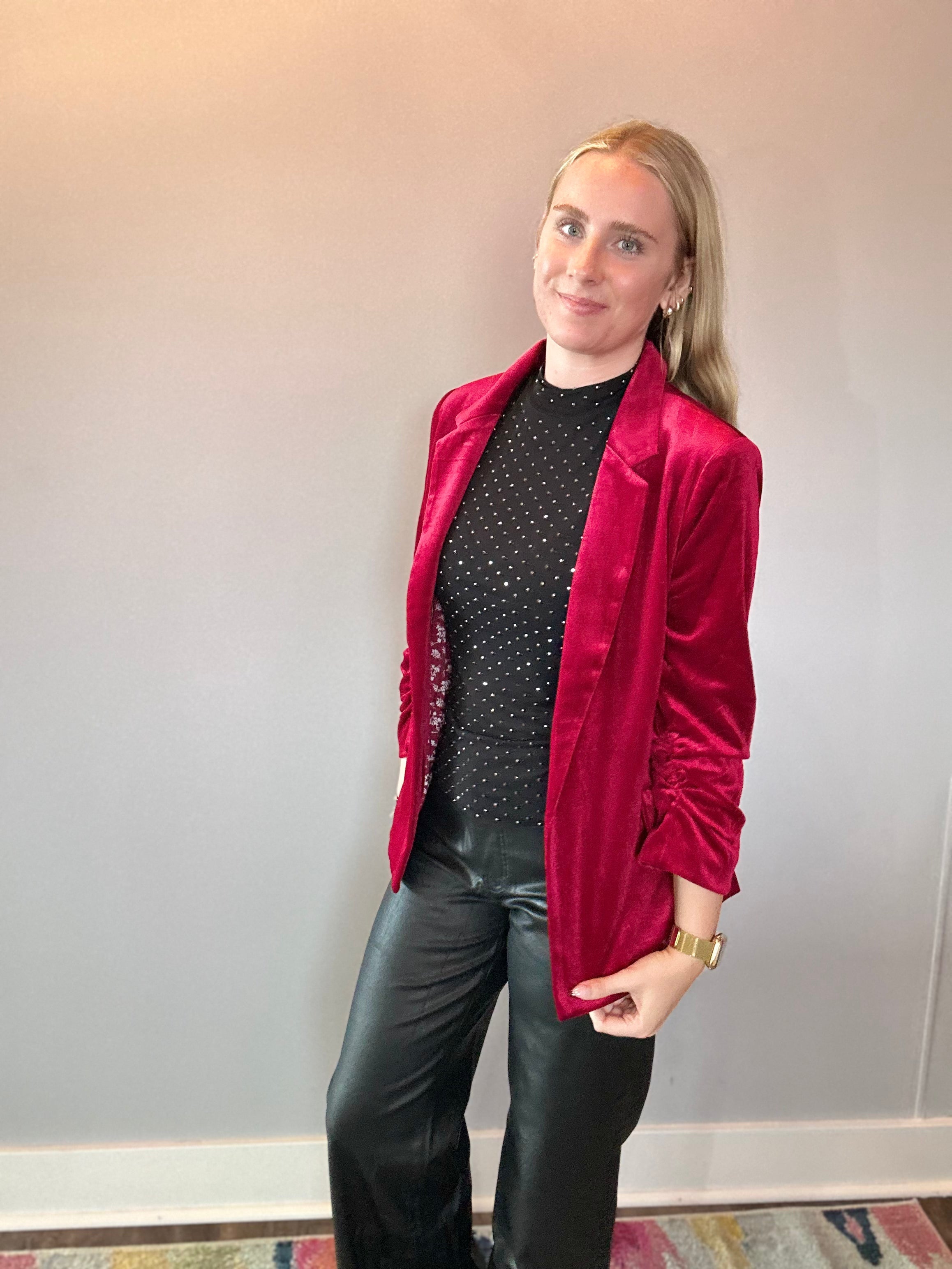 Woman styling the red velvet blazer over a graphic tee with denim for a casual look