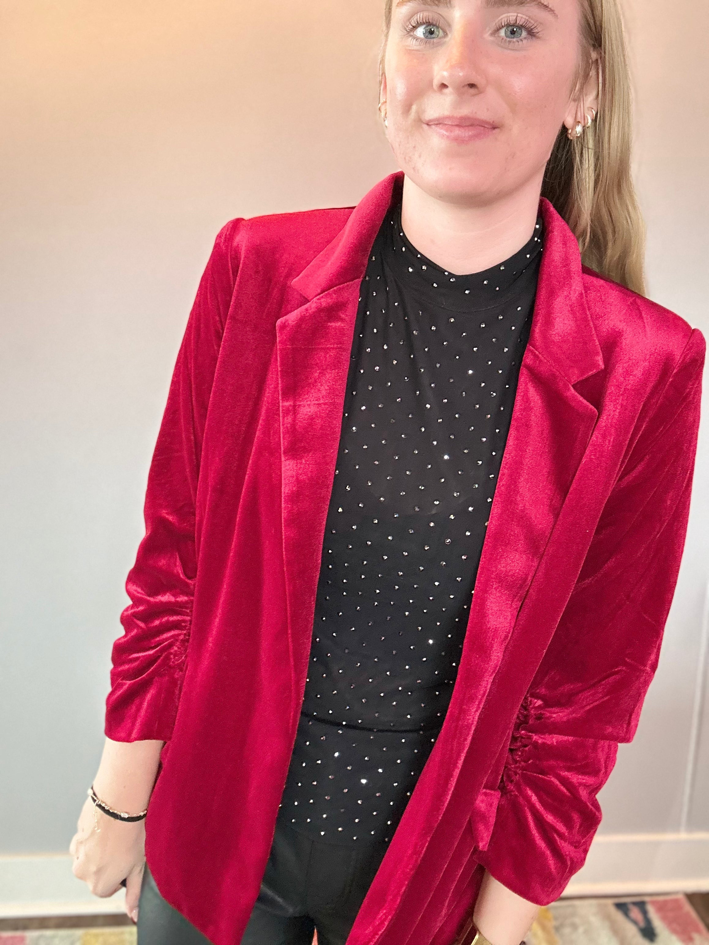 Side view of the tailored red velvet blazer showing the sleeve length and hip-length cut