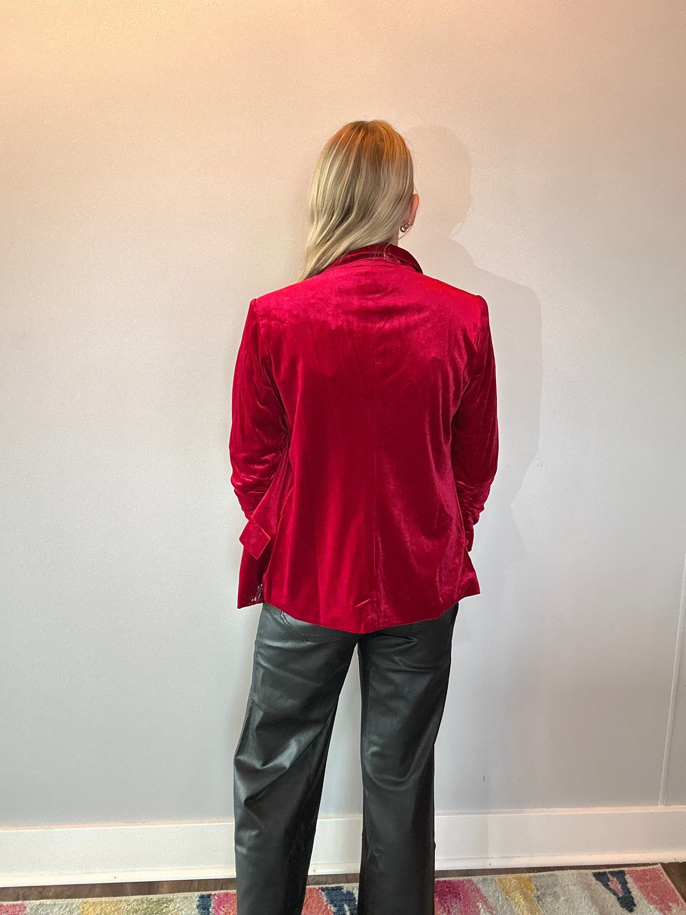 Detail of the rich red velvet texture and soft sheen across the shoulder seam of the blazer
