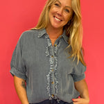Woman wearing a relaxed mineral wash denim button-up shirt with short cuffed sleeves