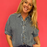 Woman wearing a relaxed mineral wash denim button-up shirt with short cuffed sleeves