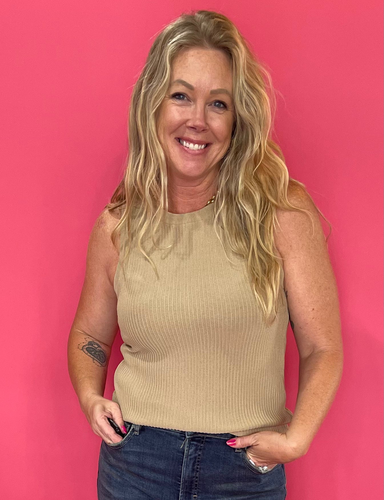 Woman wearing a mocha ribbed sweater knit tank tucked into high waisted denim with a belt