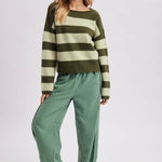 Full length view of the brown and sky blue striped boatneck sweater styled with wide leg pants