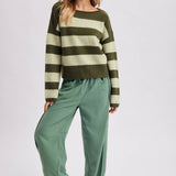 Full length view of the brown and sky blue striped boatneck sweater styled with wide leg pants