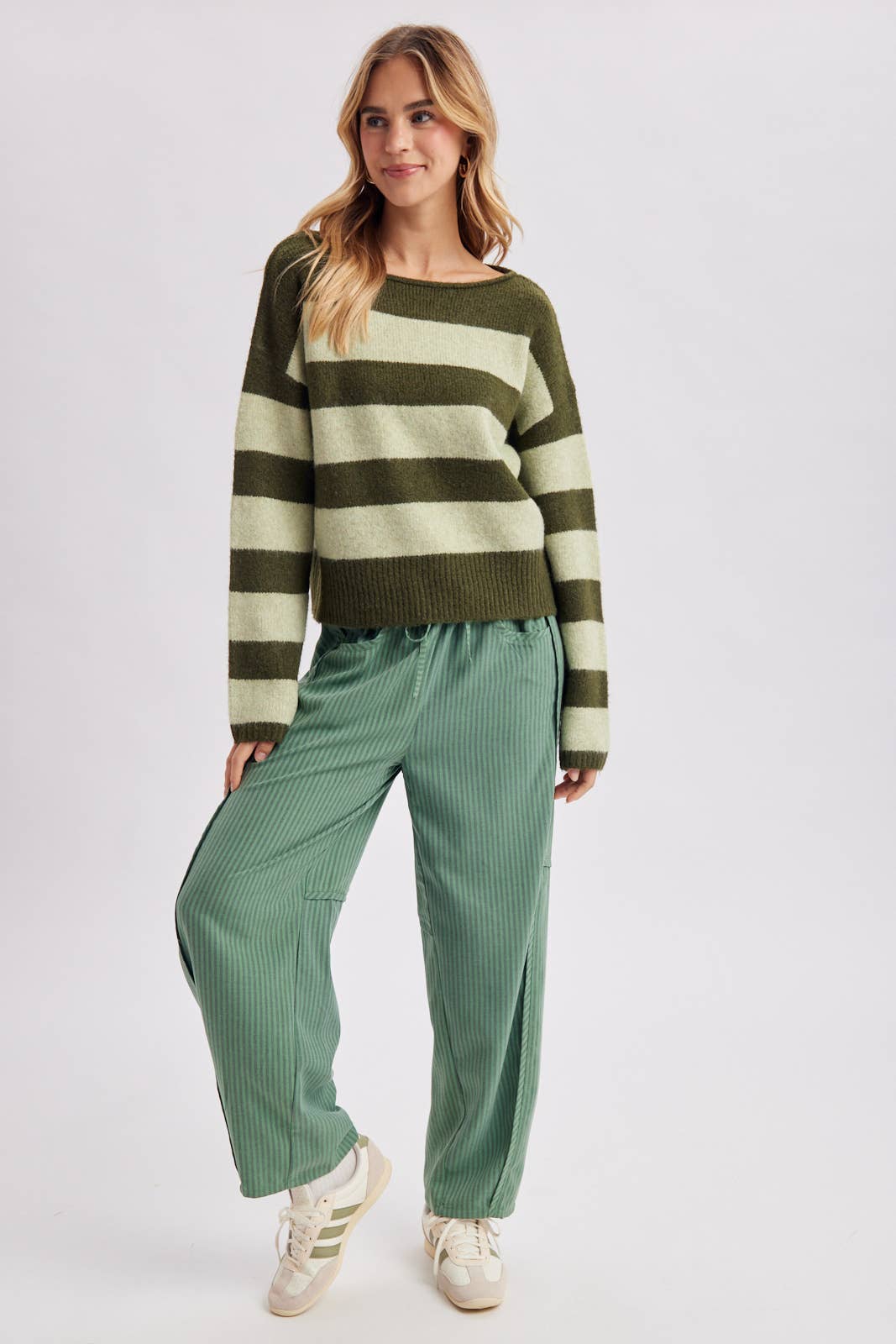 Full length view of the brown and sky blue striped boatneck sweater styled with wide leg pants