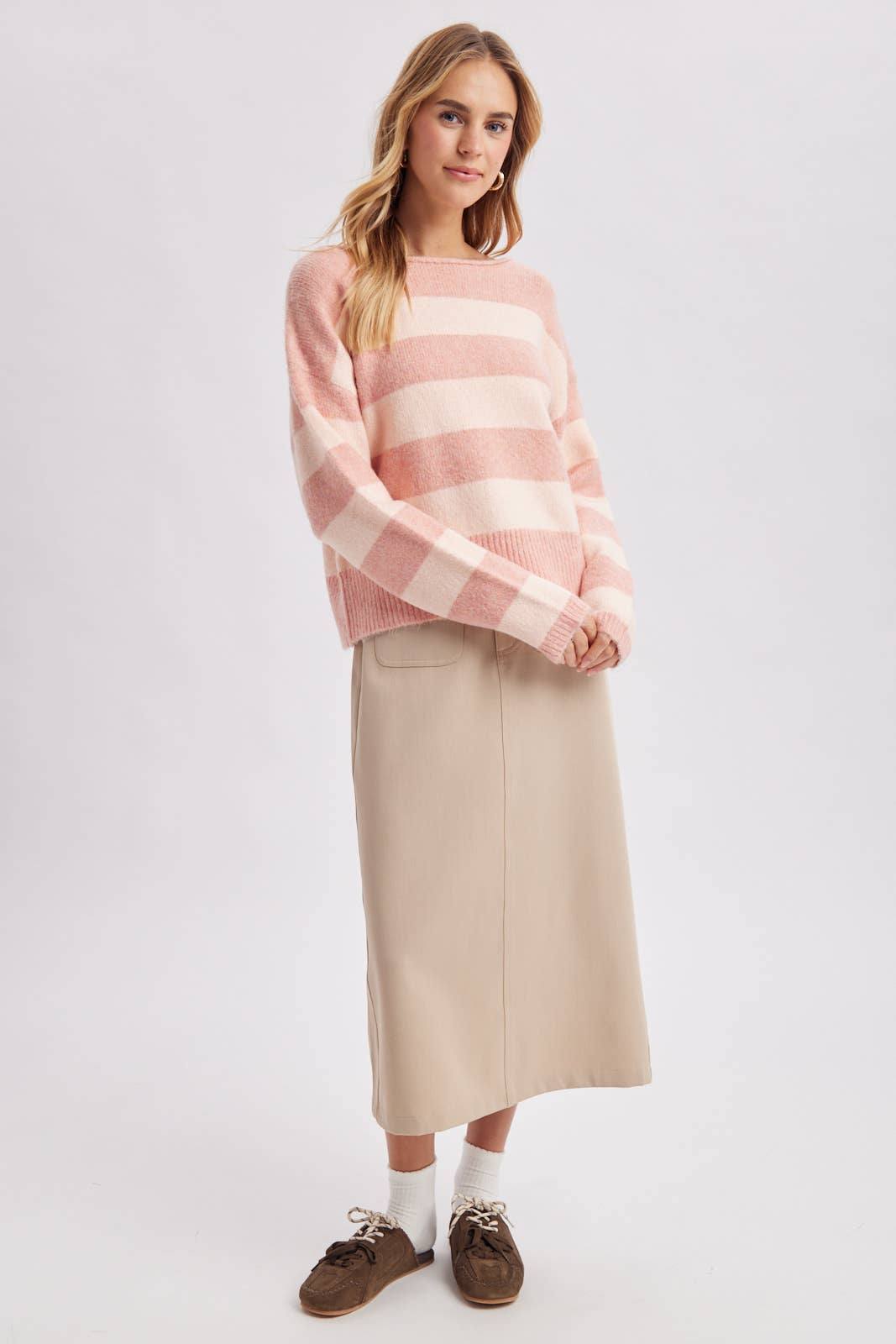 Side view of the striped boatneck sweater in brown and sky blue worn with a relaxed drape
