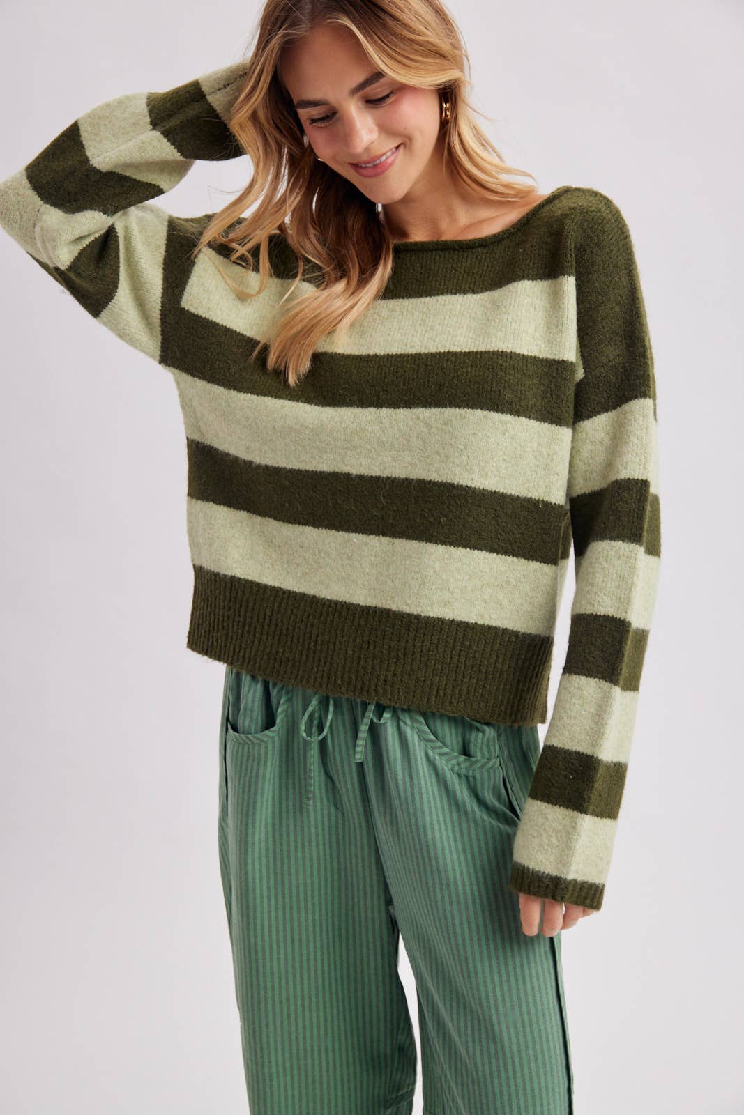 Front view of the relaxed fit striped sweater in brown and sky blue worn untucked over pants