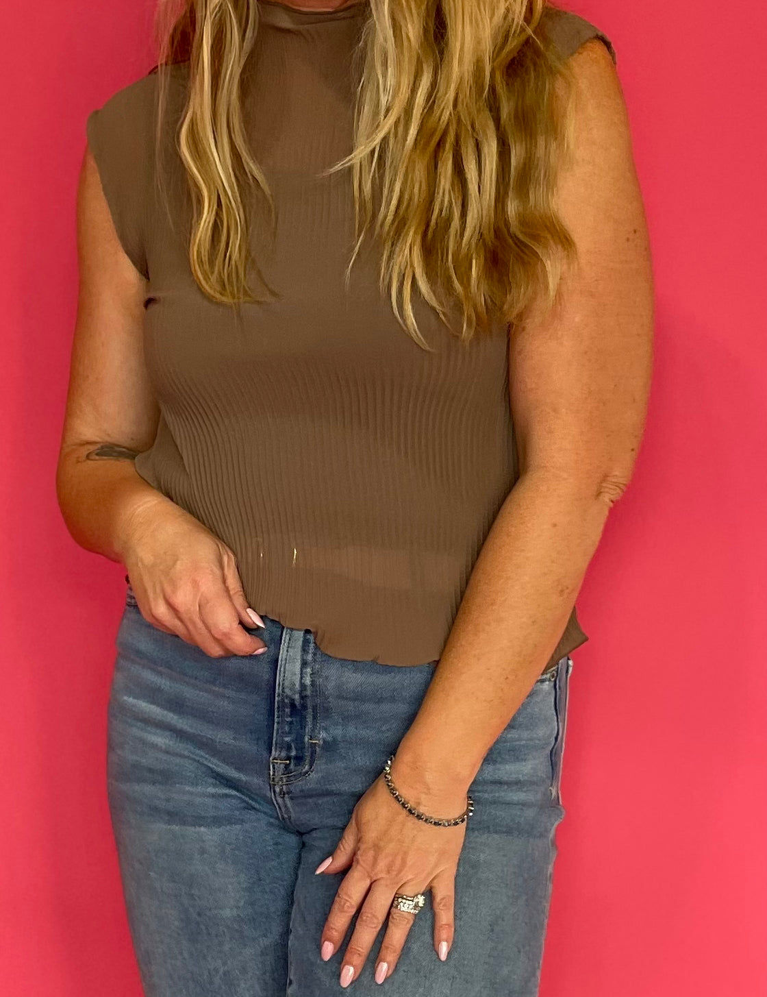 Woman wearing a mocha sheer plisse mock neck sleeveless blouse layered over a cami