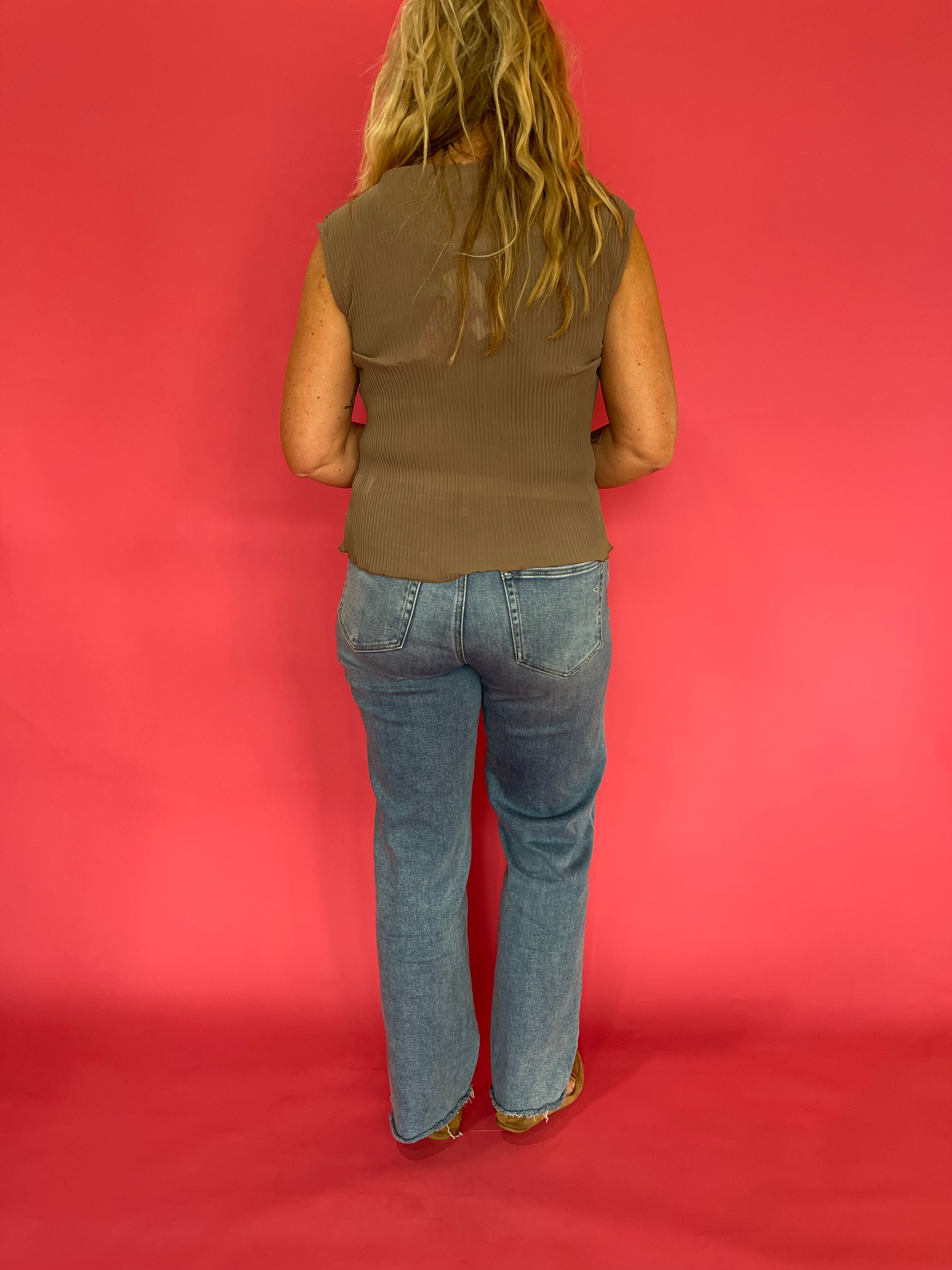 Full length view of the mocha sheer plisse mock neck blouse tucked into tailored trousers