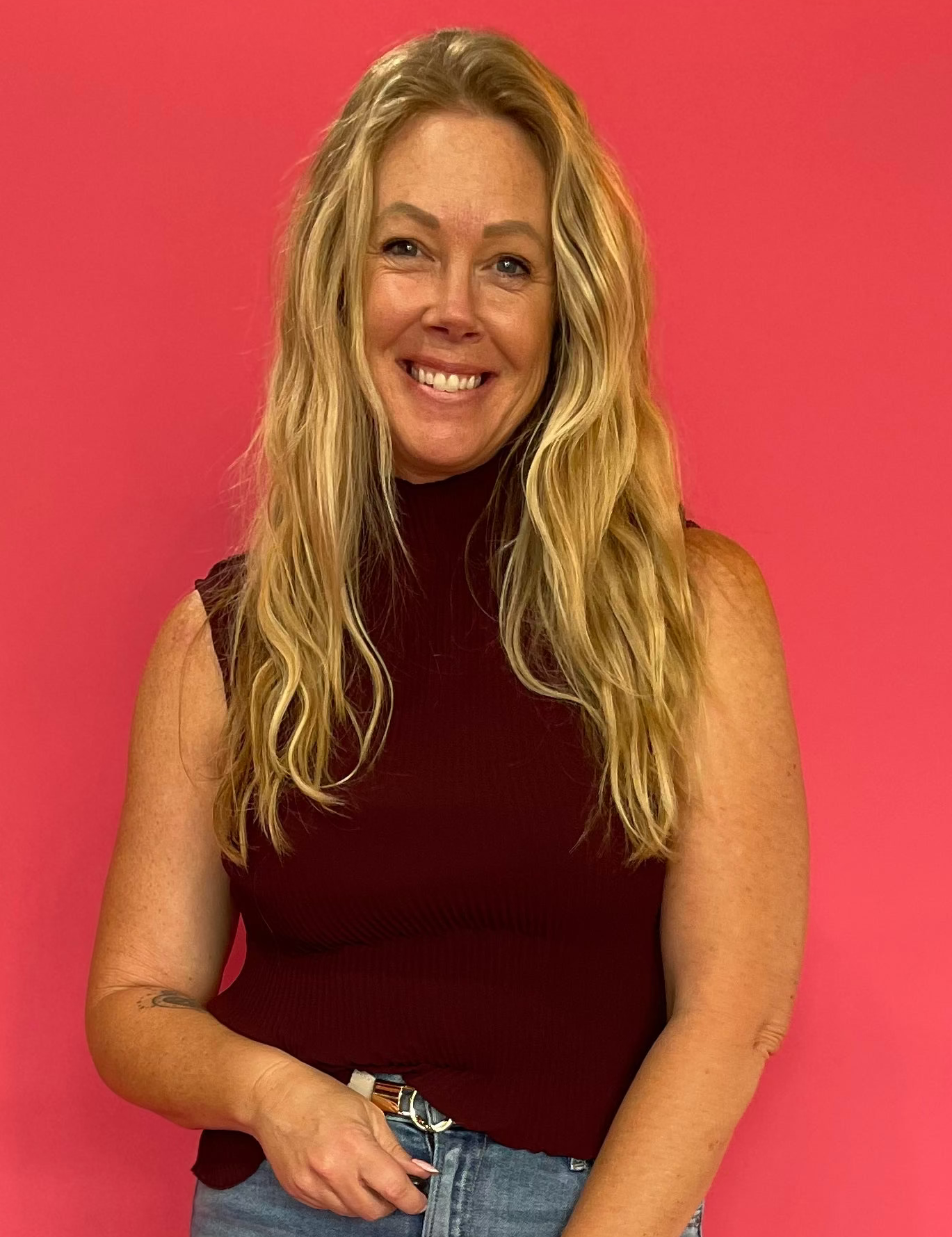 Woman wearing an oxblood sheer plisse mock neck sleeveless blouse layered over a matching cami
