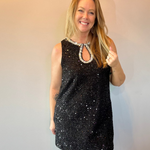 Woman wearing a black sequin sleeveless mini dress with a beaded neckline and heels