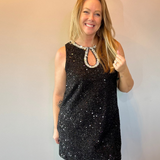 Woman wearing a black sequin sleeveless mini dress with a beaded neckline and heels