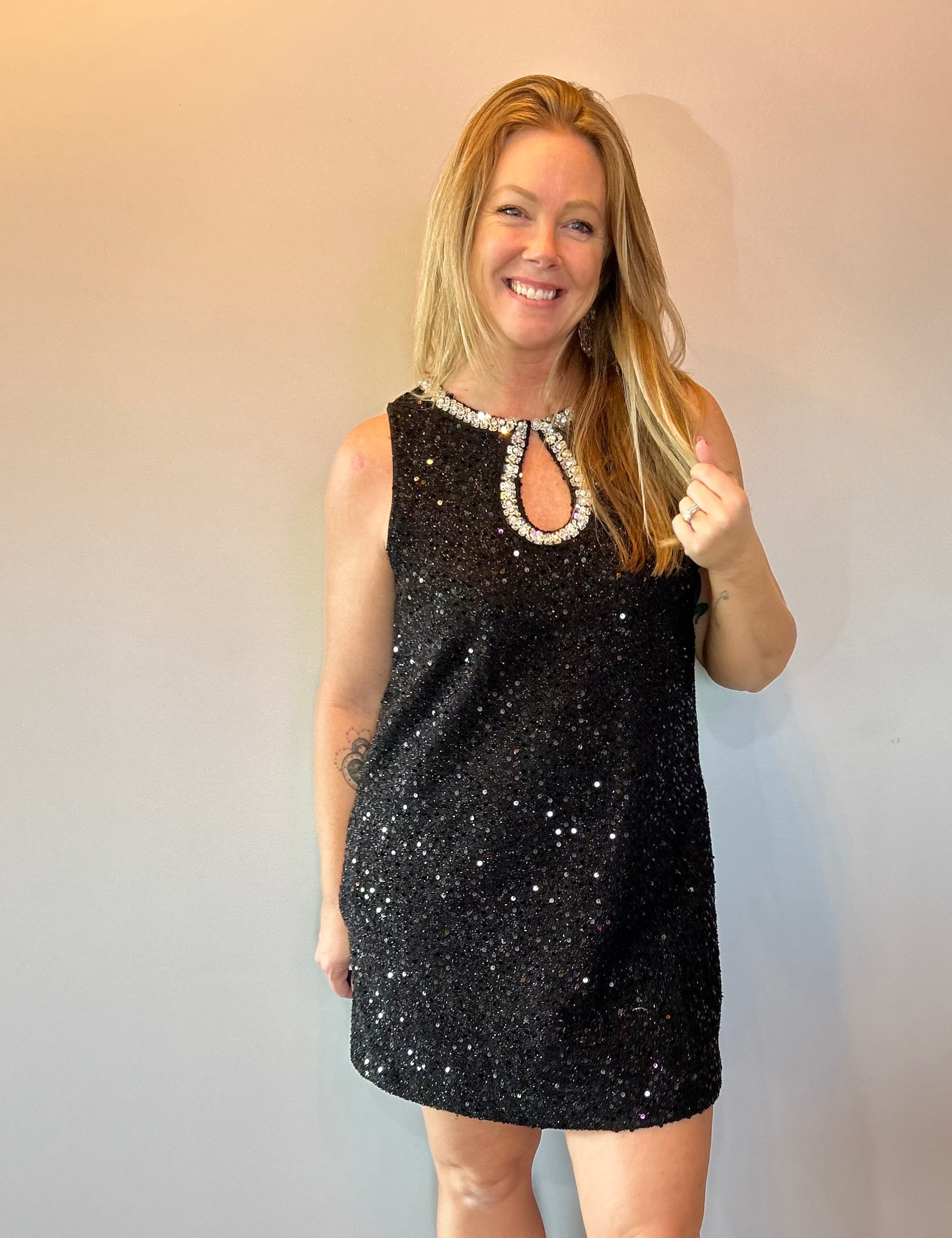Woman wearing a black sequin sleeveless mini dress with a beaded neckline and heels
