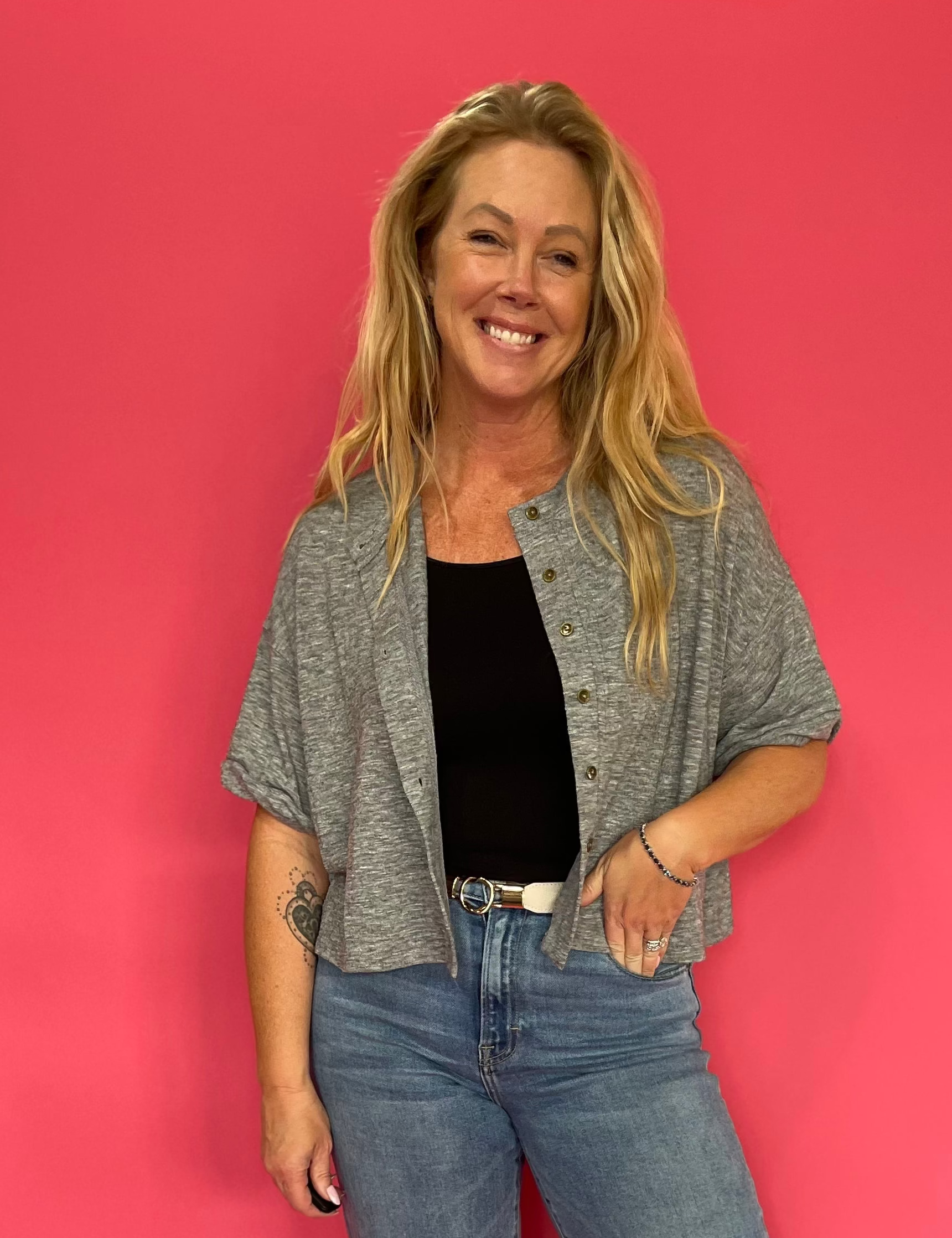 Woman wearing a heather grey short sleeve knit top with a functional button front