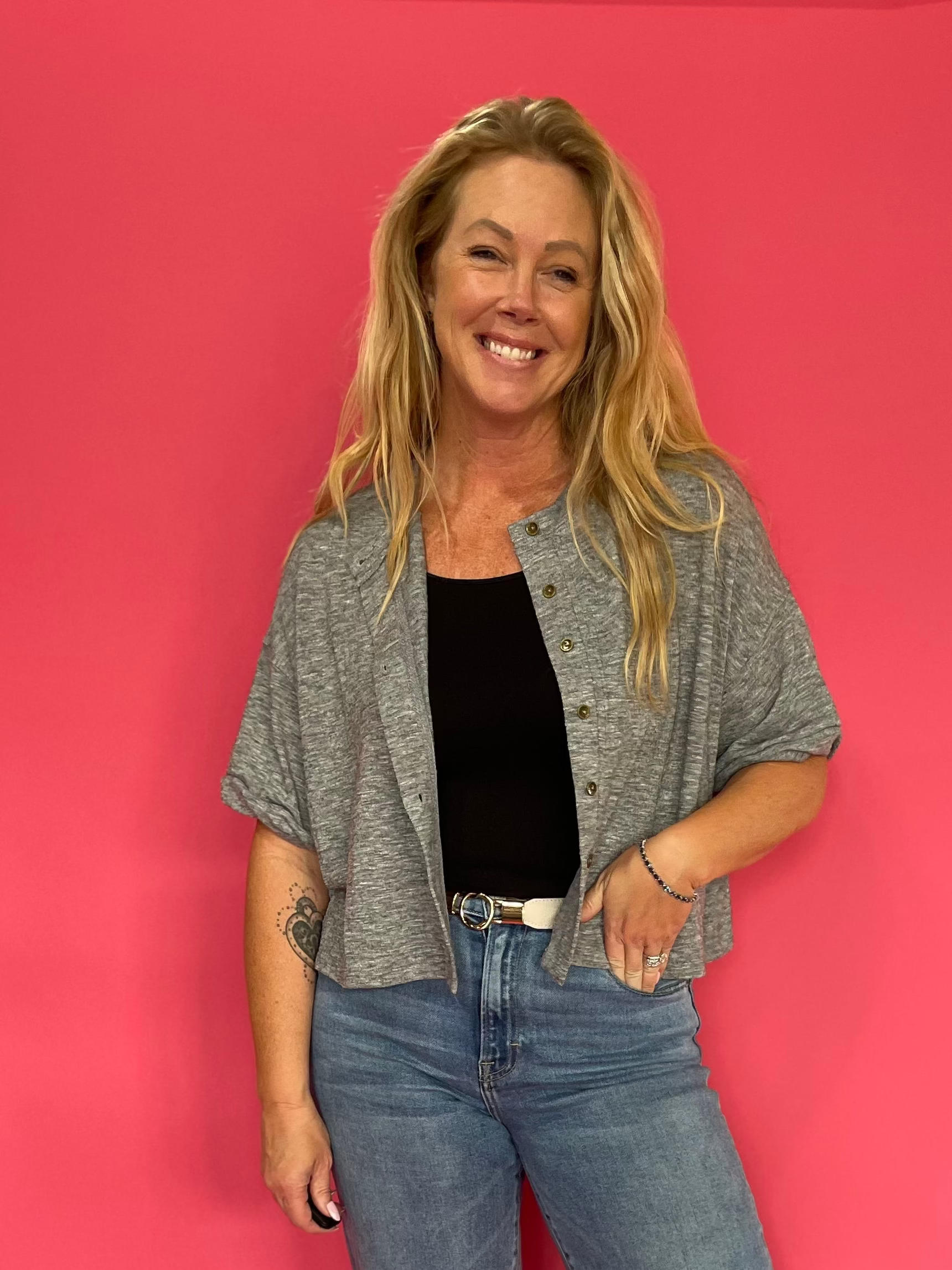 Woman wearing a heather grey short sleeve knit top with a functional button front