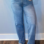 Woman wearing high rise straight leg jeans in a classic medium wash with a roomy vintage fit