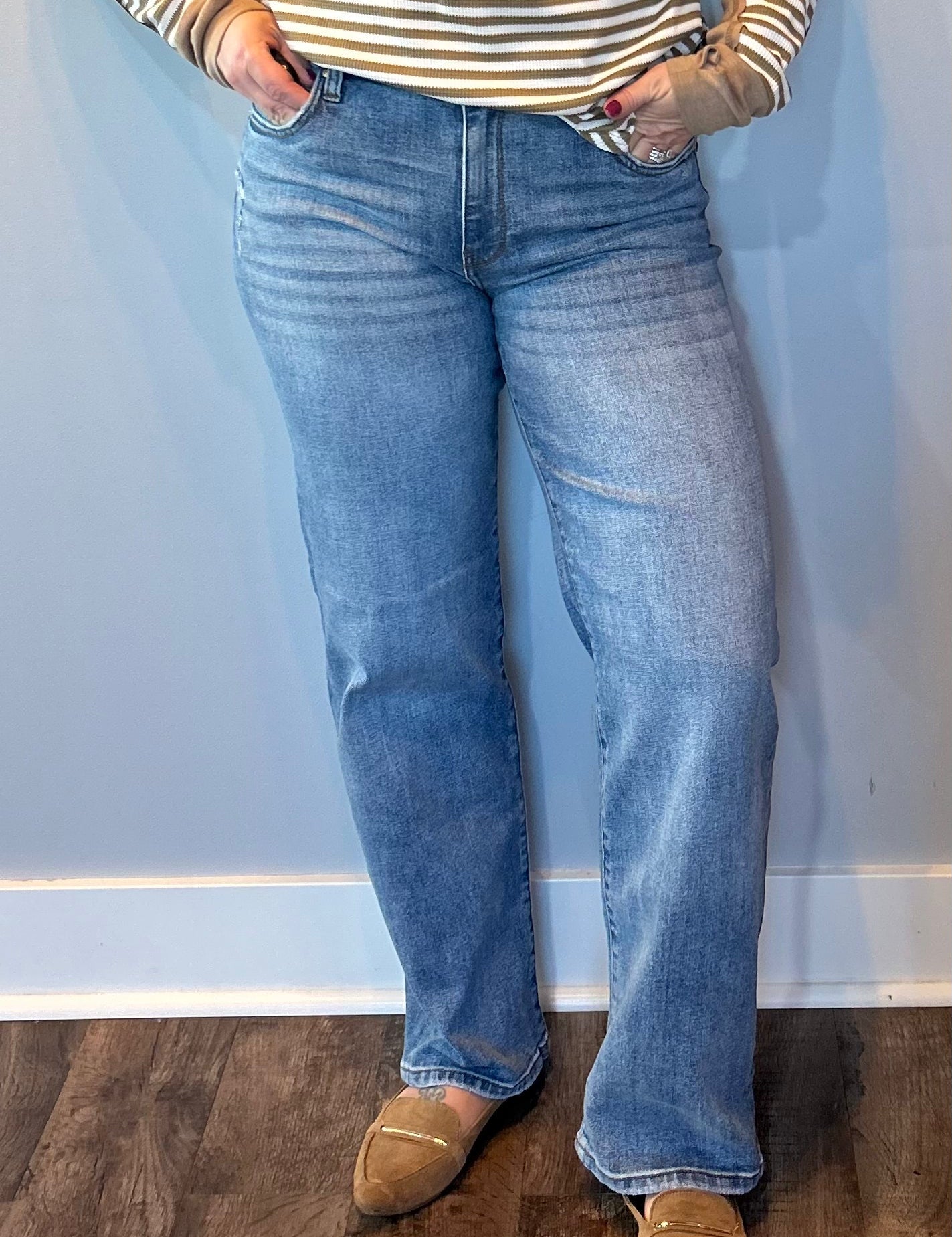 Woman wearing high rise straight leg jeans in a classic medium wash with a roomy vintage fit