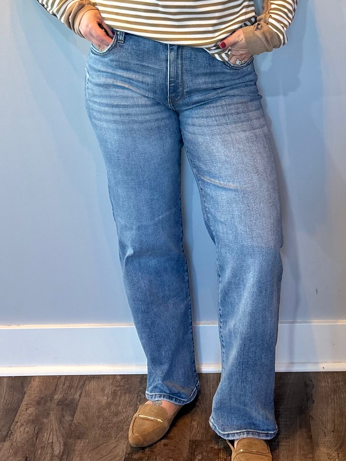 Woman wearing high rise straight leg jeans in a classic medium wash with a roomy vintage fit