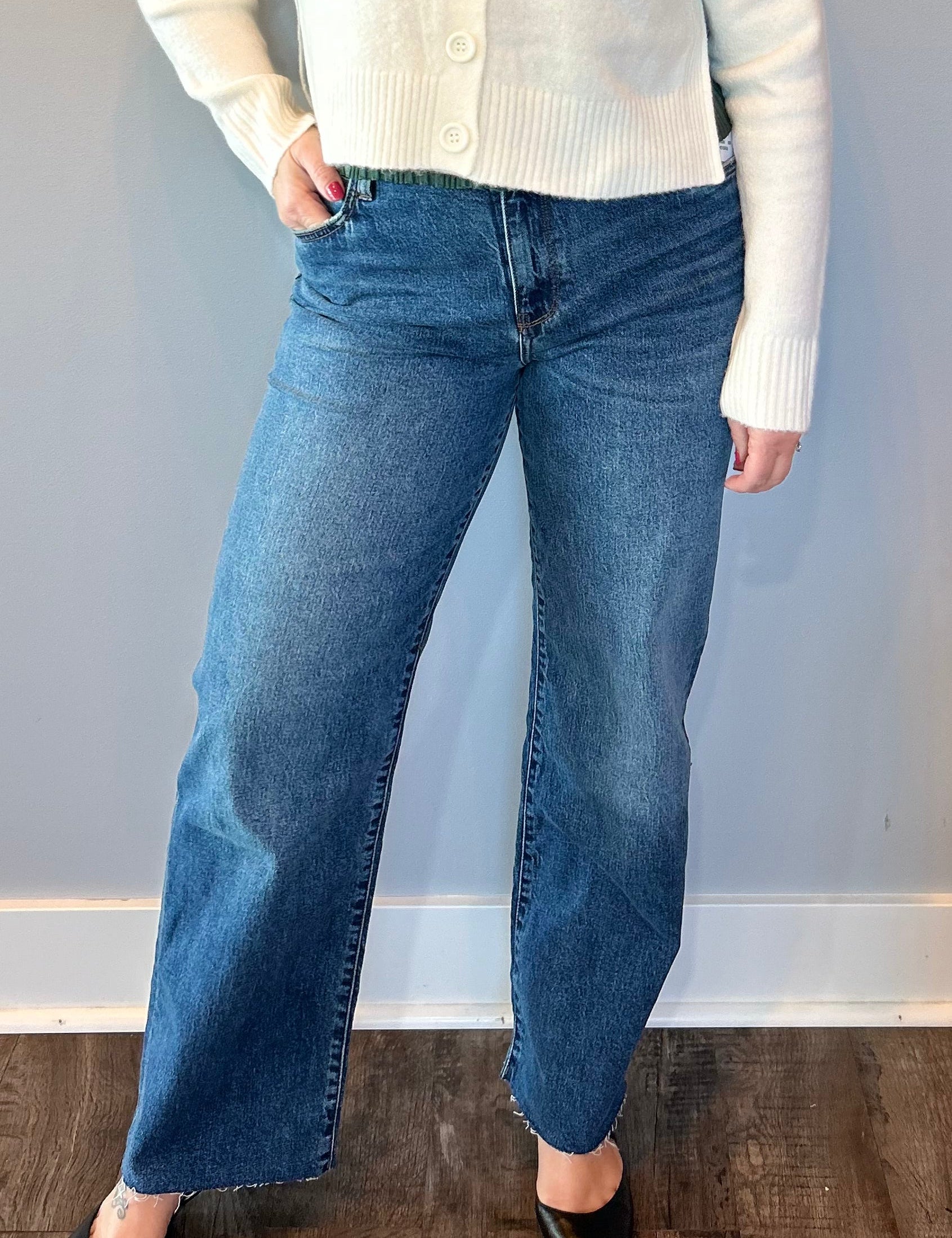 Woman wearing high rise straight leg jeans with a frayed raw hem and a tucked in top