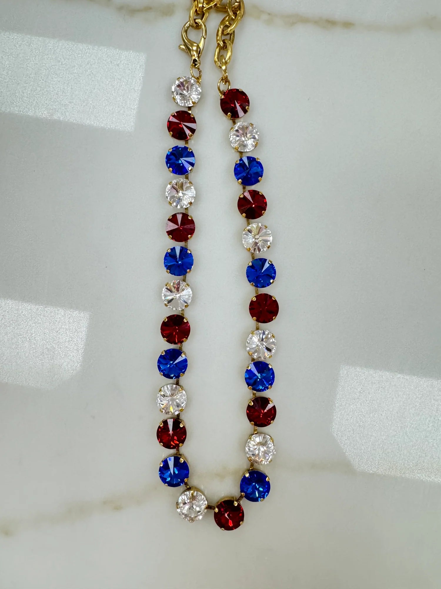 Antique gold plated Tova Sofia necklace set with multicolor 4th of July mix crystals on a plain backdrop