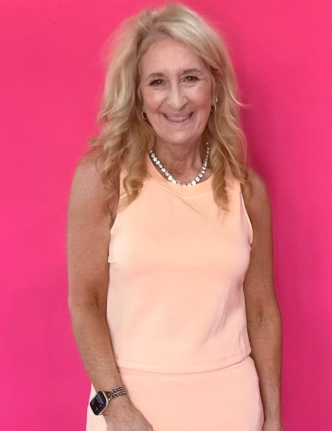 Woman wearing a peach modal sleeveless top with a scoop neckline and soft flowy drape