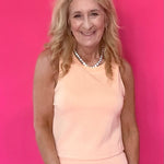 Woman wearing a peach modal sleeveless top with a scoop neckline and soft flowy drape