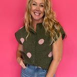Woman wearing an olive green knit sweater top with blush polka dots, a collar and button front