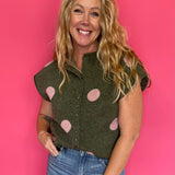 Woman wearing an olive green knit sweater top with blush polka dots, a collar and button front