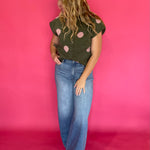 Close-up of the collar and button front placket on the olive green polka dot sweater top