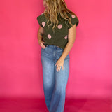 Close-up of the collar and button front placket on the olive green polka dot sweater top