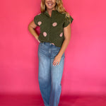 Side view of the cropped olive knit top showing the rolled short sleeve and high hip hem