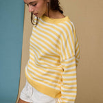 Woman wearing a yellow and white striped sweater against a beige wall.