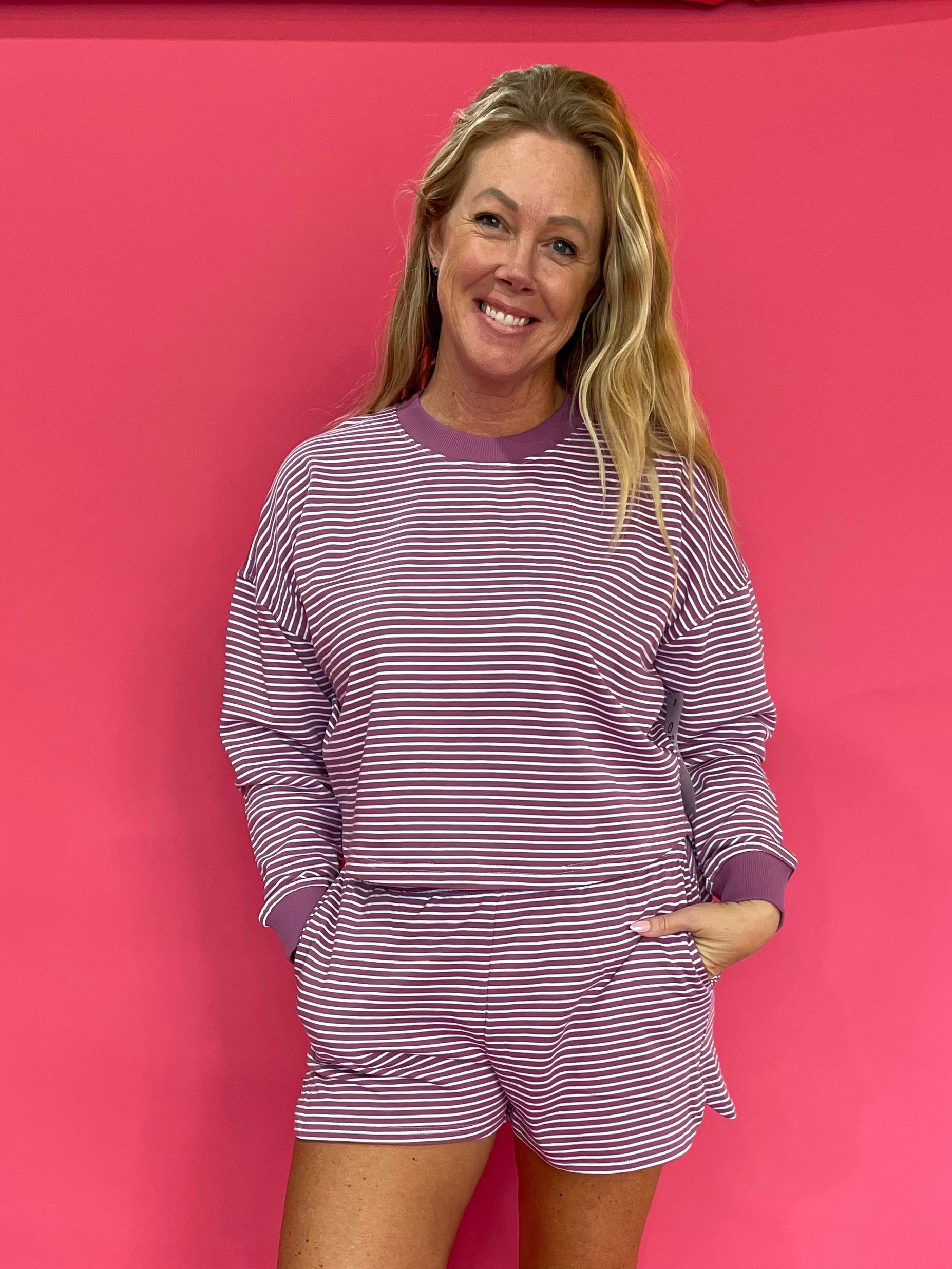 Woman wearing a mulberry and cream striped cropped French terry crewneck with matching shorts
