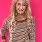 Woman wearing a green and cream striped long sleeve crop top with drop shoulders and high-rise straight leg jeans