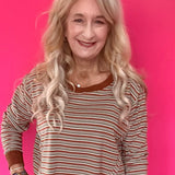 Woman wearing a green and cream striped long sleeve crop top with drop shoulders and high-rise straight leg jeans