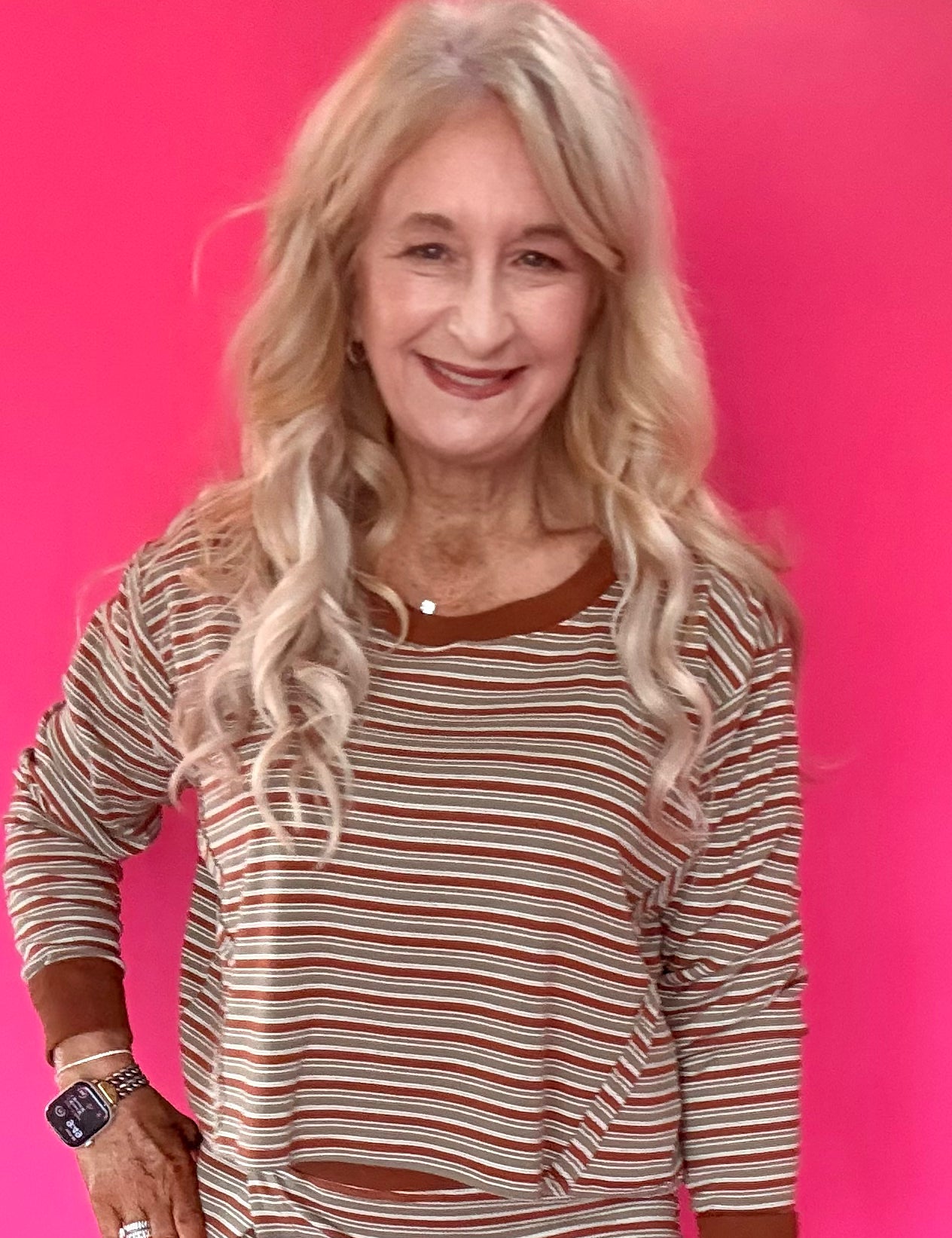 Woman wearing a green and cream striped long sleeve crop top with drop shoulders and high-rise straight leg jeans