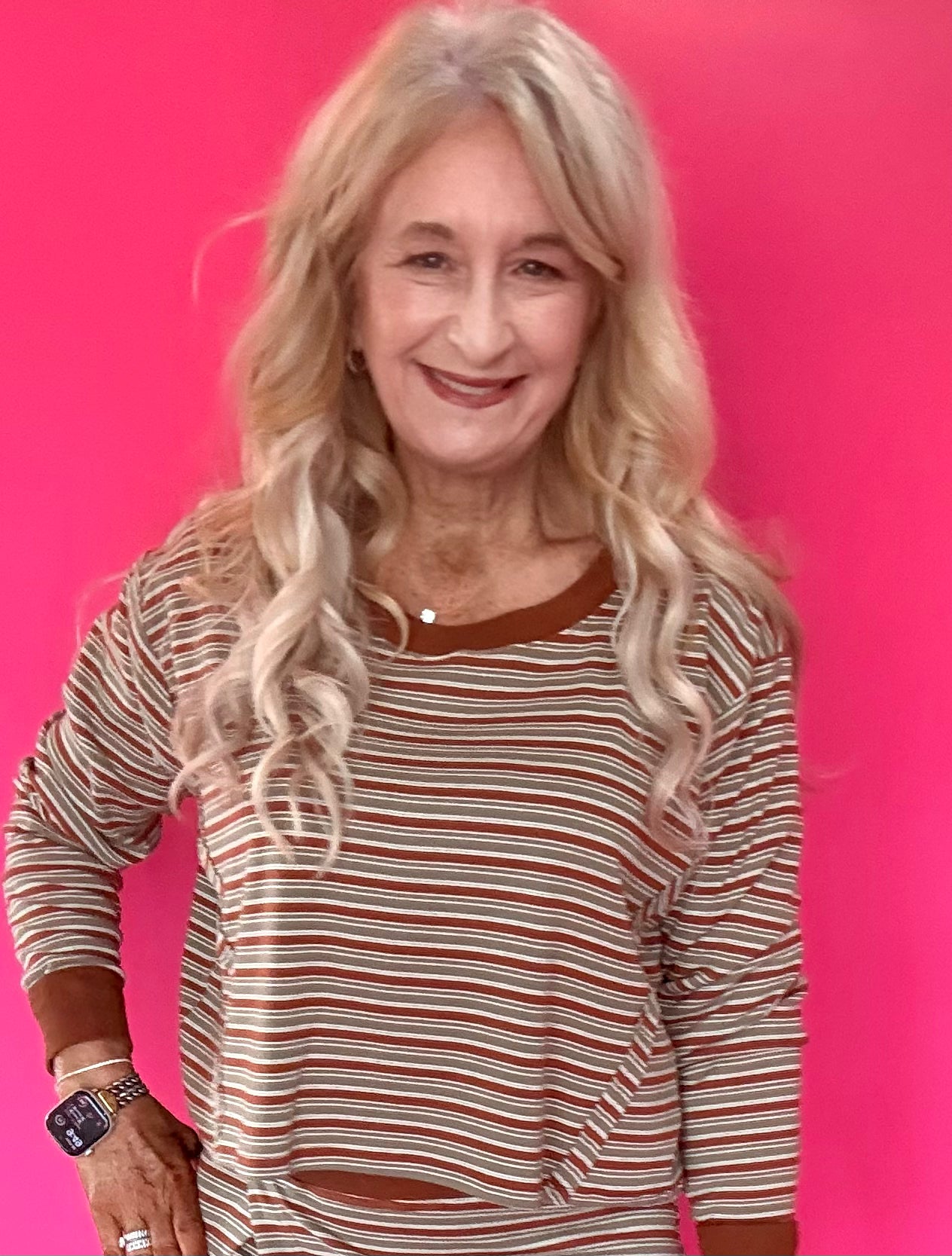 Woman wearing a green and cream striped long sleeve crop top with drop shoulders and high-rise straight leg jeans