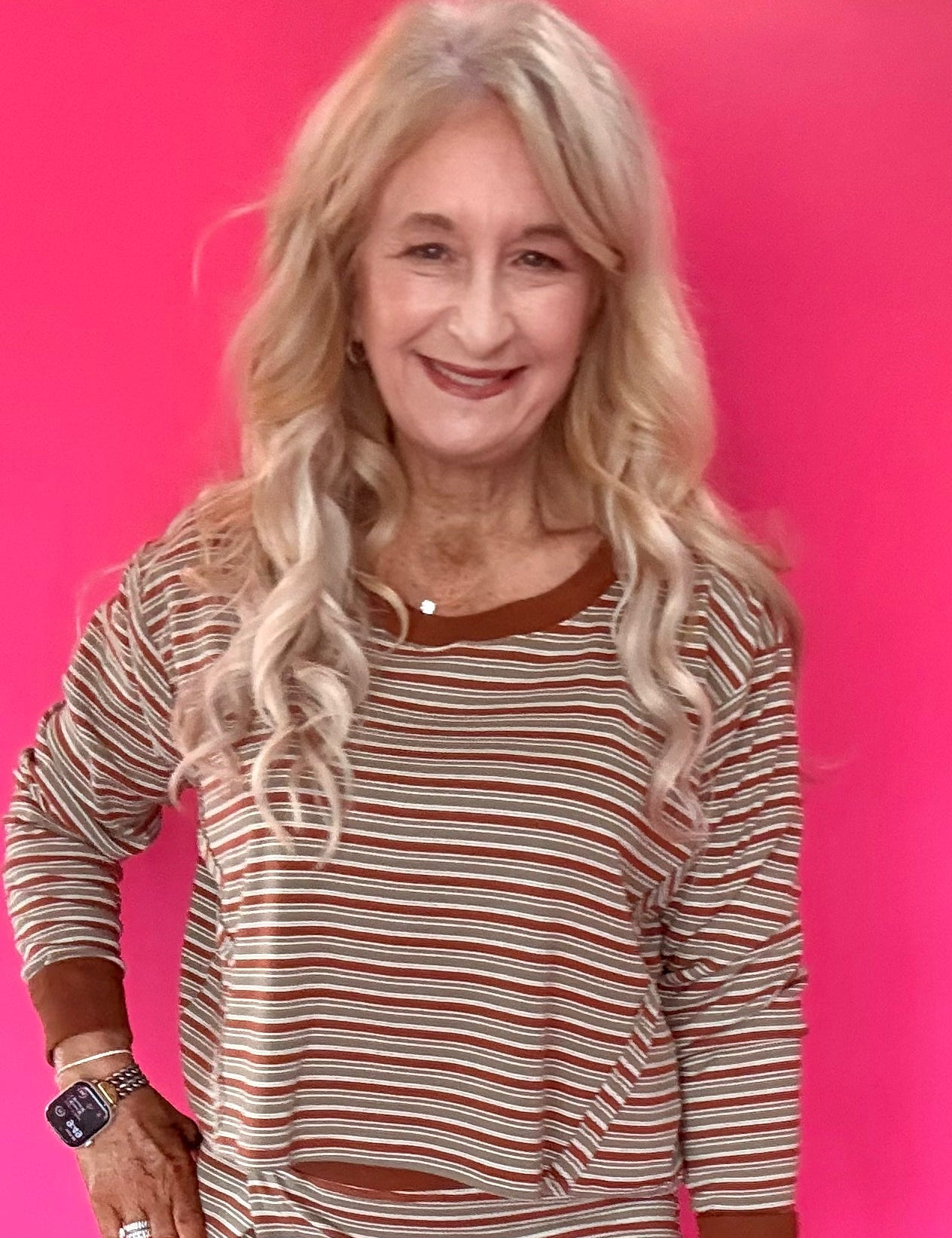 Woman wearing a green and cream striped long sleeve crop top with drop shoulders and high-rise straight leg jeans