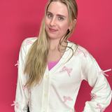 Woman wearing a white blouse with pink patterns and a black polka dot skirt against a pink background