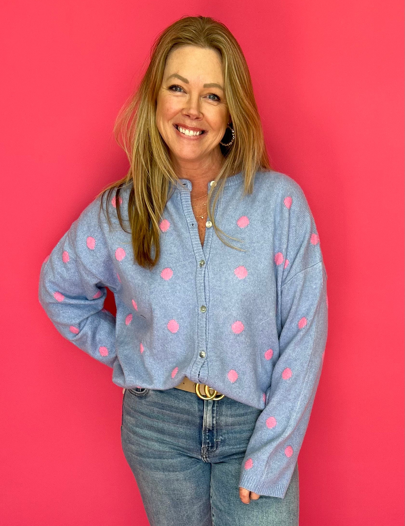 Woman wearing a blue shirt with pink polka dots against a red background