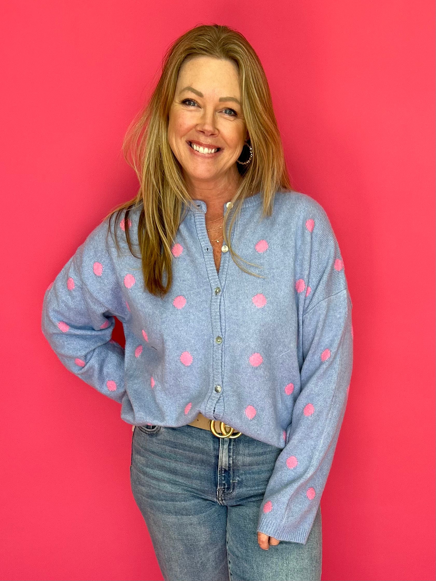 Woman wearing a blue shirt with pink polka dots against a red background