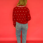 Side view of the red heart print button-up sweater showing the long sleeves and soft drape