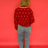 Side view of the red heart print button-up sweater showing the long sleeves and soft drape